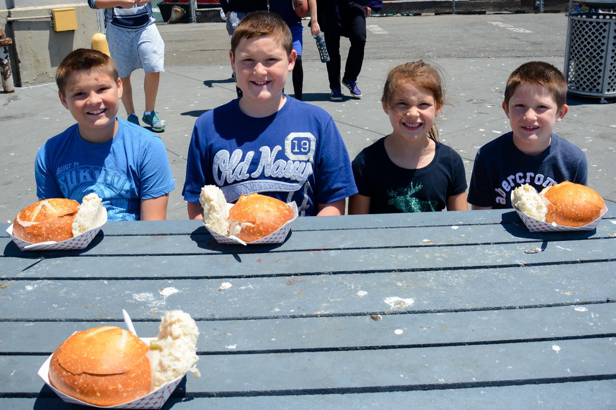 Smiling kids with clam chowder bread bowls in San Francisco