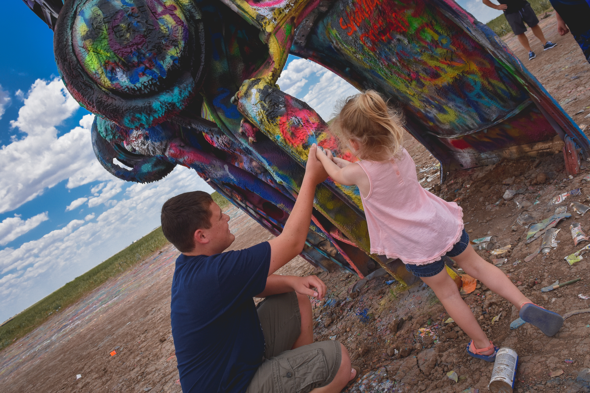 Teen boy and young girl spray painting a Cadillac