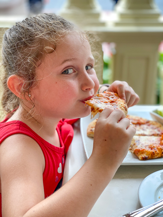 girl eating pizza outdoors