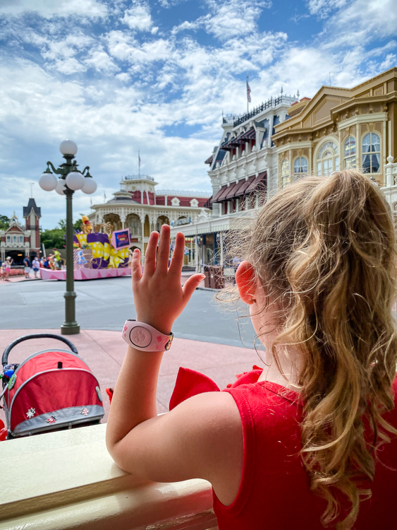 girl waving at character cavalcade Main Street Magic Kingdom