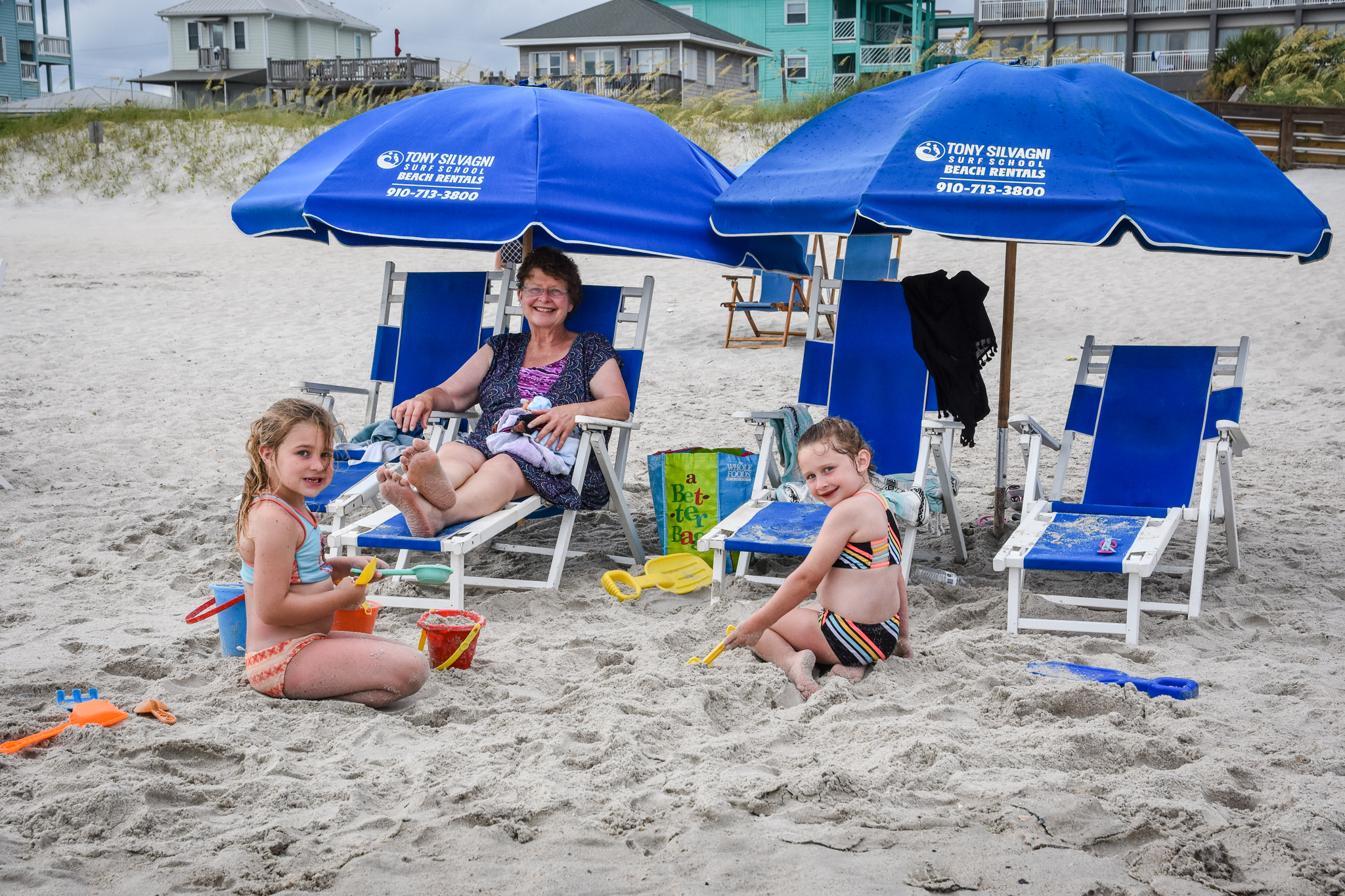 Smiling family at the beach with rented beach chairs and umbrellas
