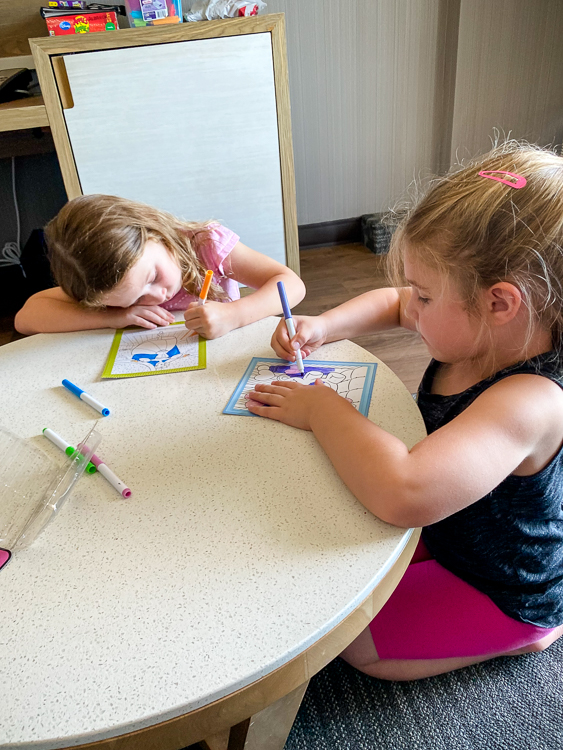 two girls coloring in a hotel room