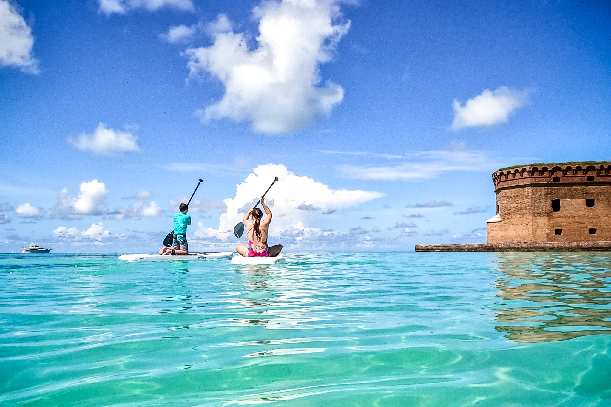 2 teens paddleboarding in the blue/green Gulf of Mexico at Dry Tortugas