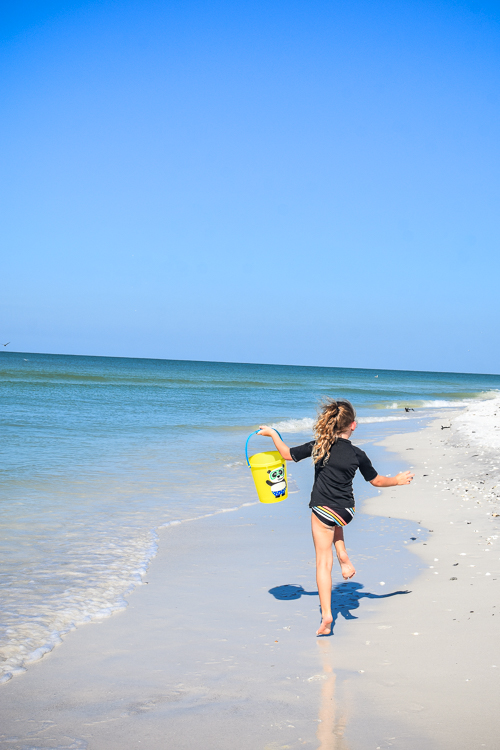 Girl happily skipping along beach Keewaydin Island with kids