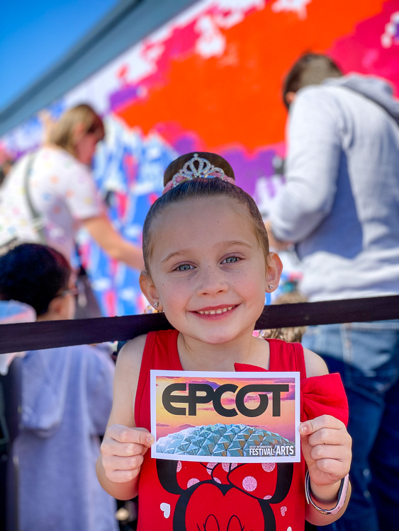 Smiling girl with the finished print at the paint by number mural at EPCOT