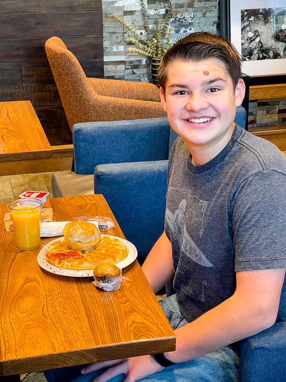Smiling teen with a hotel waffle for breakfast