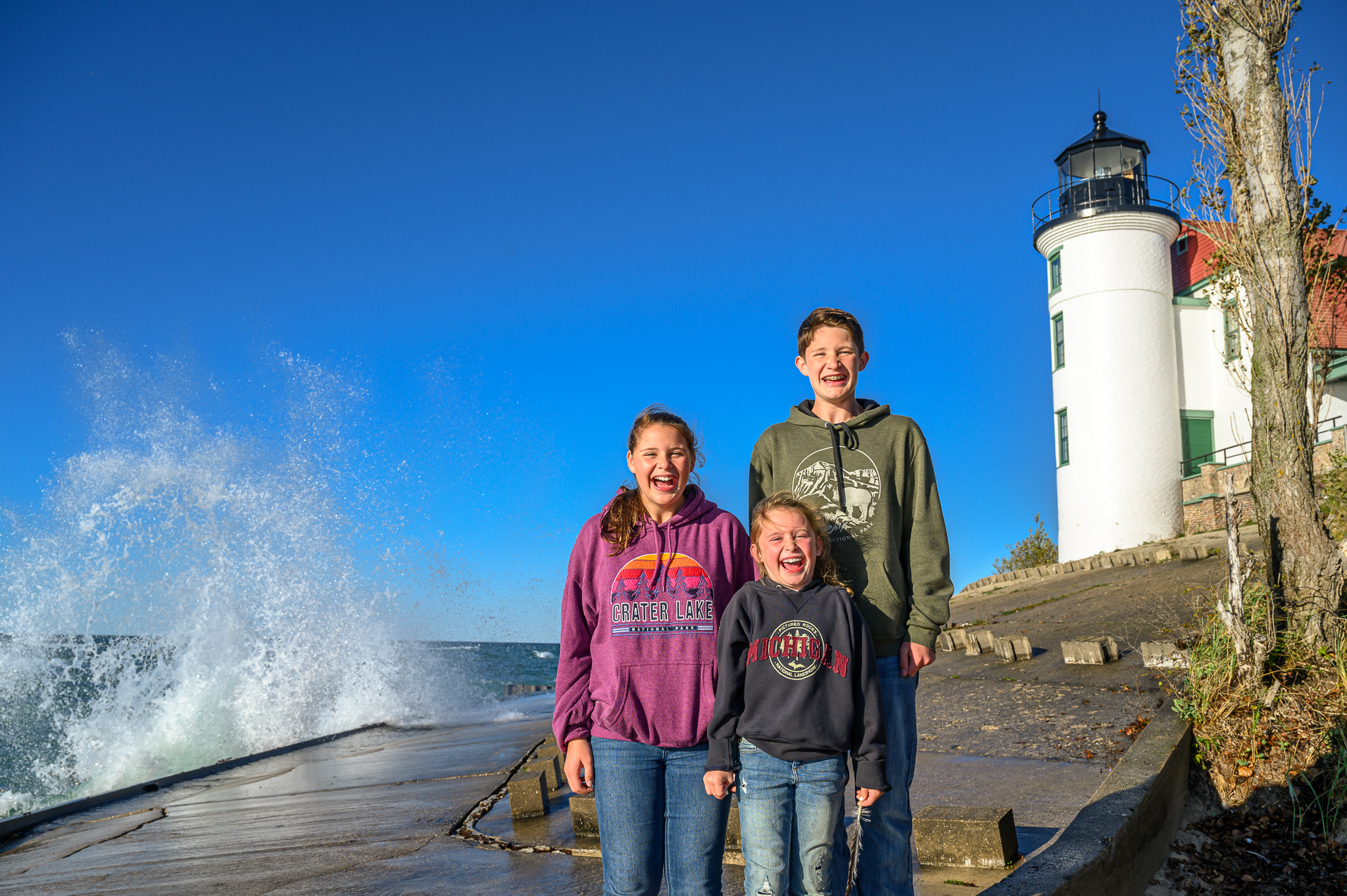 Point Betsie Lighthouse with waves of Lake Michigan splashing kids on the shore