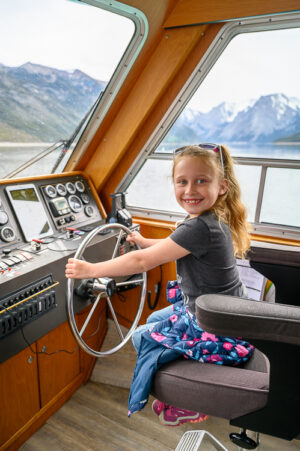 girl steering boat on Lake Minnewanka Banff